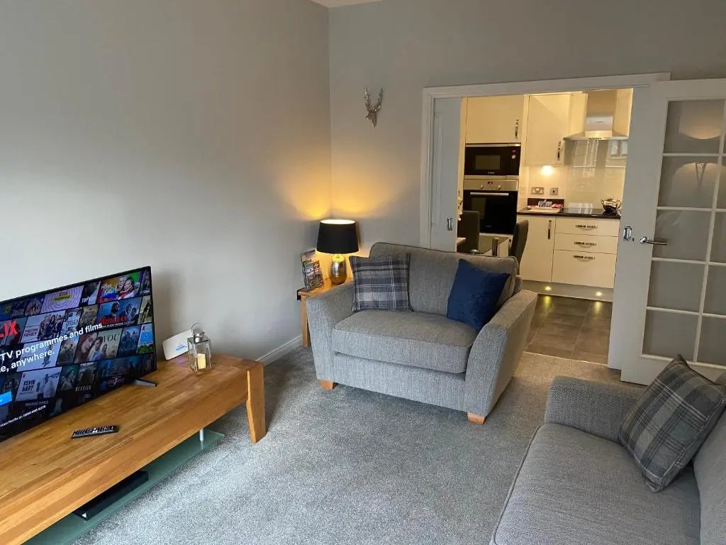 a living room with a couch and a television at 23 Hedgefield House in Inverness