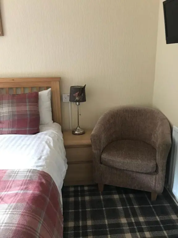 a bedroom with a chair and a bed and a pillow at Foyers Roost in Foyers