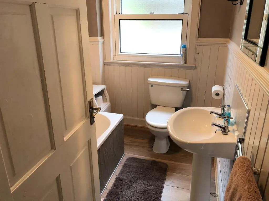 a bathroom with a toilet and a sink and a window at Rose Cottage in Inverness