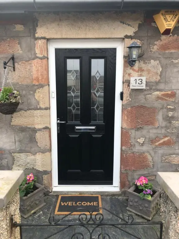 a black door with a welcome sign in front of a building at Rose Cottage in Inverness