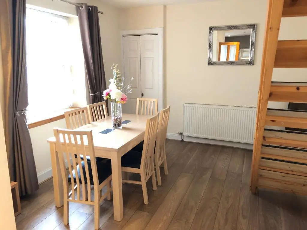 a dining room table with chairs and a vase of flowers at Rose Cottage in Inverness