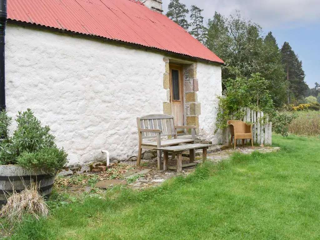 a bench in front of a white building with a red roof at St Orans in Rafford