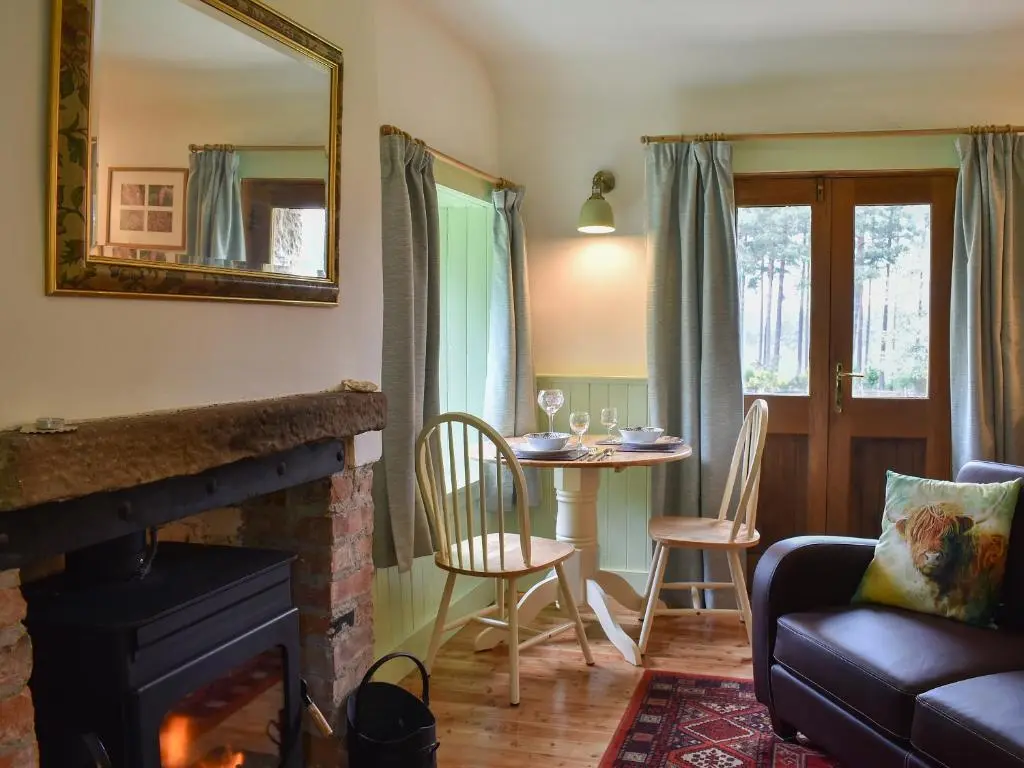 a living room with a fireplace and a table with chairs at St Orans in Rafford