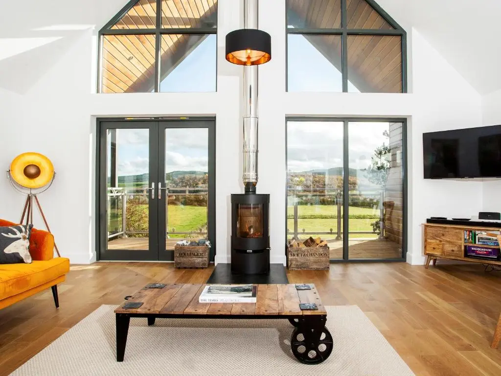 a living room with a table and a fireplace at Strathspey Lodge in Duthil