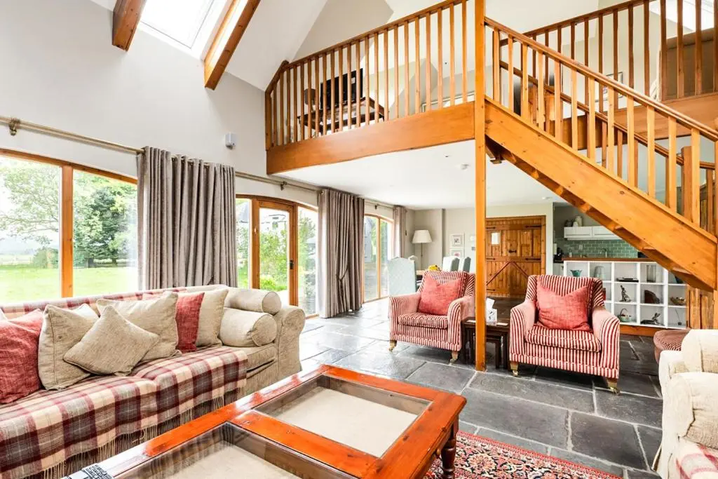 a living room with couches and a staircase at Coach House at Soilzarie in Blairgowrie