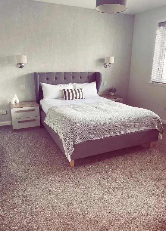 a bedroom with a large bed with a purple headboard at Malva - Modern 2 Bedroom Bungalow in Wick Sleeps 4 with private parking - NC500 Route in Wick