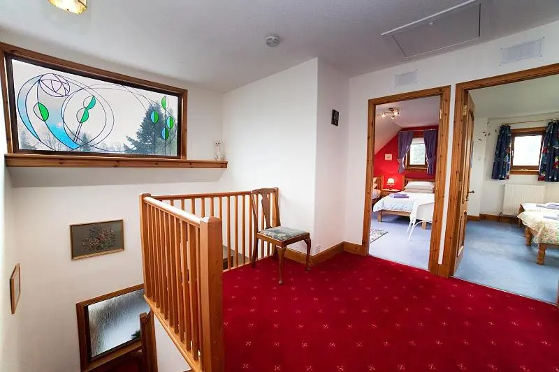a living room with a red carpet and a stair case at Rowans Inverness in Inverness