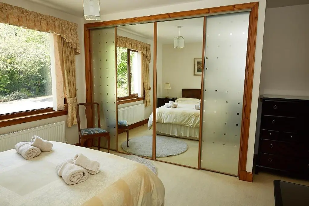a bedroom with two beds and a mirror at Rowans Inverness in Inverness