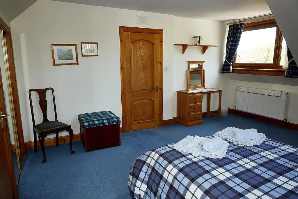 a bedroom with a bed and a chair and a window at Rowans Inverness in Inverness