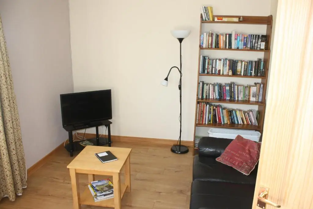 a living room with a couch and a book shelf filled with books at Inver bay apartment in Tain