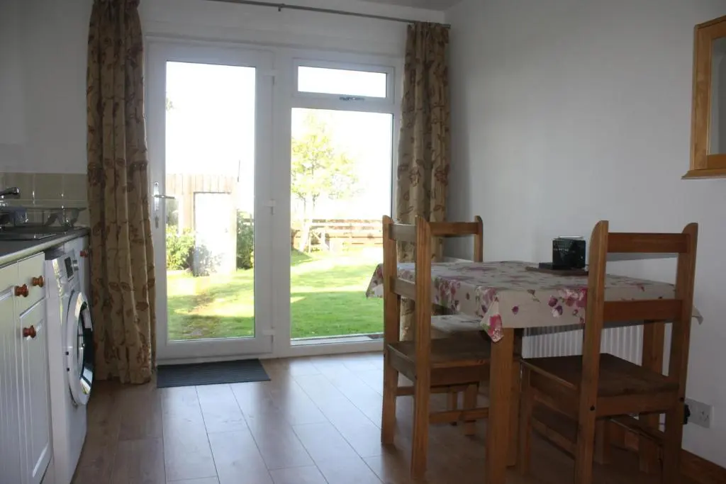 a kitchen with a table and chairs and a door at Inver bay apartment in Tain