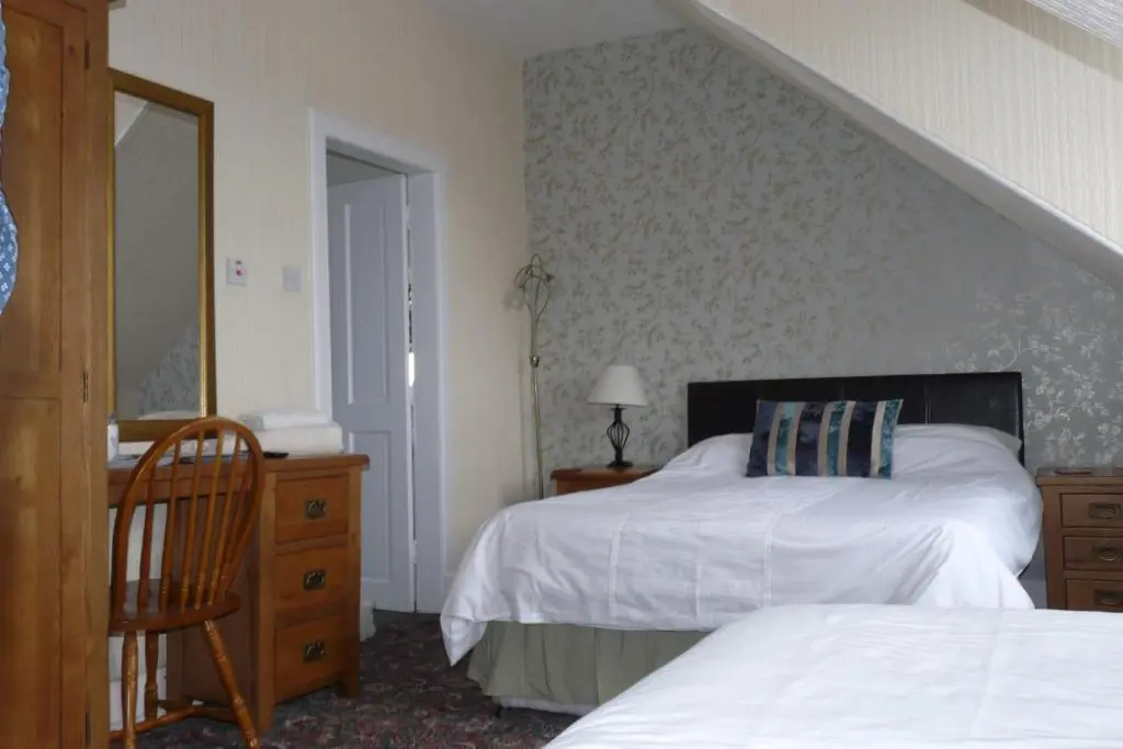a bedroom with two beds and a mirror and a staircase at Bank Guest House in Wick