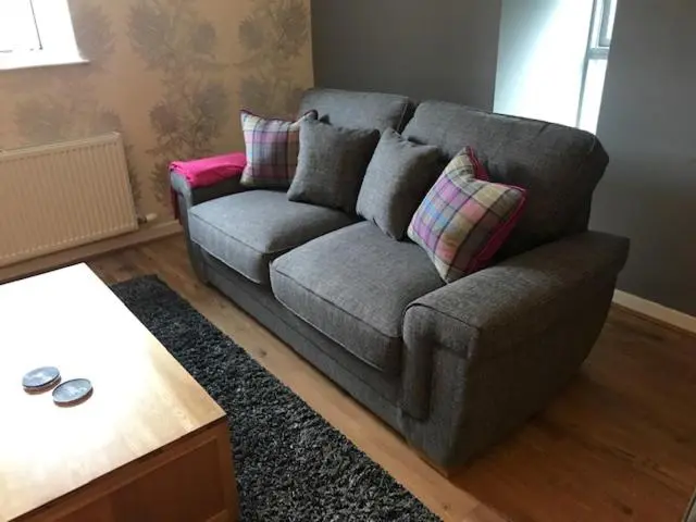 a gray couch with pillows in a living room at Lovat Loch Ness Apartment with private roof terrace in Fort Augustus