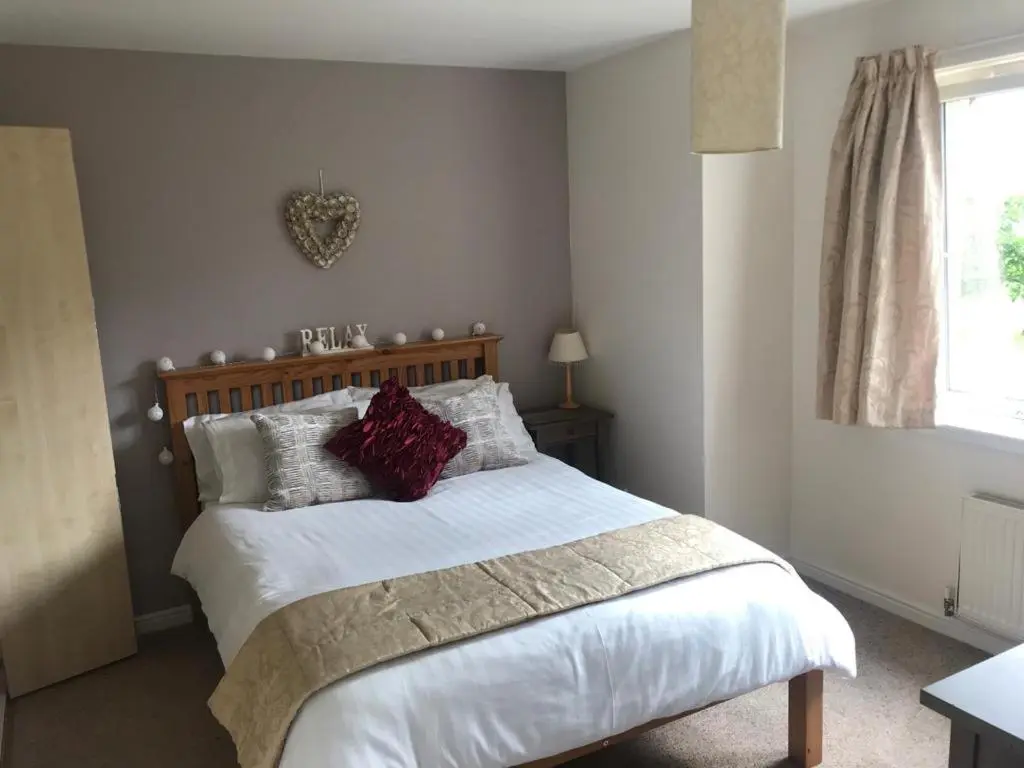 a bedroom with a bed with white sheets and red pillows at Hector's House in Aviemore