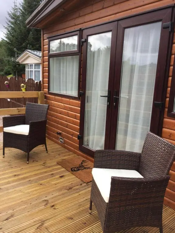 a screened in deck with two chairs and windows at Cragganmore Lodge in Aviemore