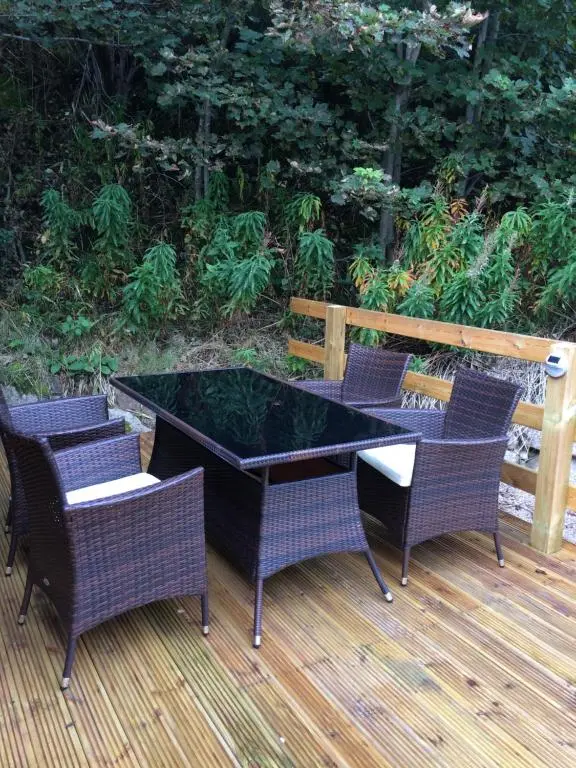 a glass table and chairs on a wooden deck at Cragganmore Lodge in Aviemore
