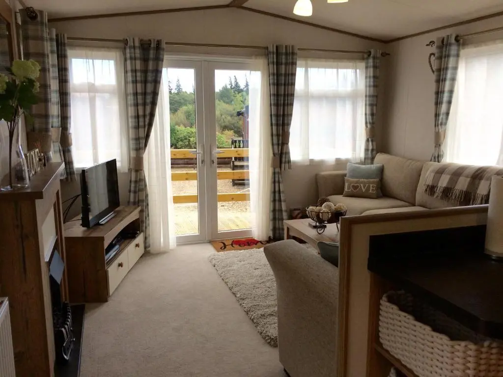 a living room with a couch and a tv at Cragganmore Lodge in Aviemore