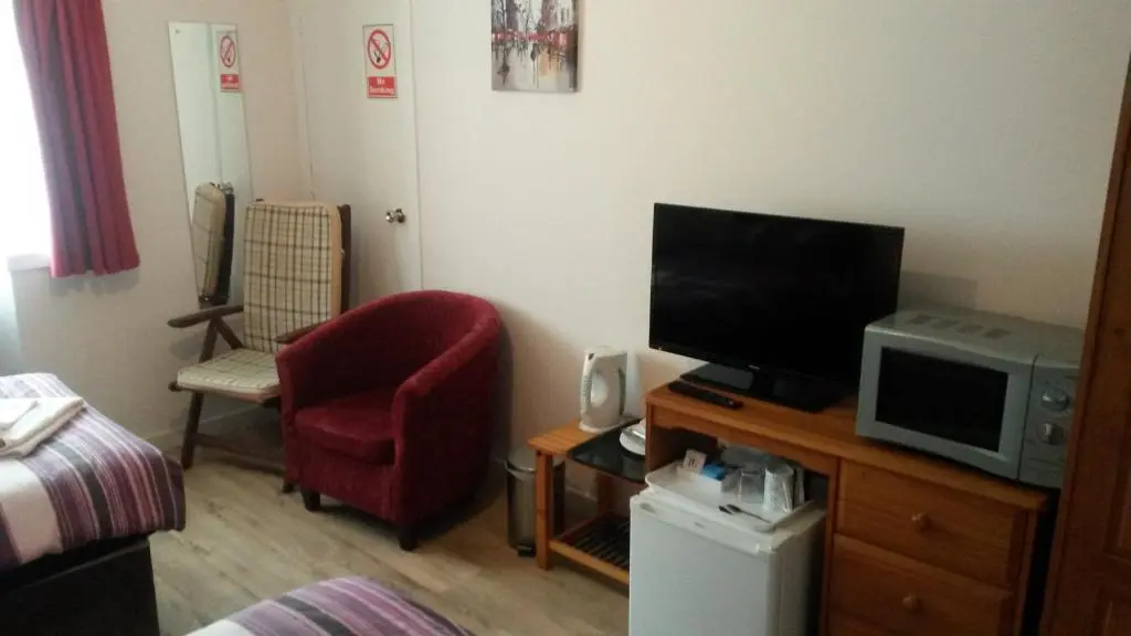 a living room with a tv and a red chair at Station View Guest House in Dyce