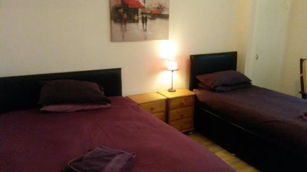 a bedroom with two beds and a lamp on a night stand at Station View Guest House in Dyce