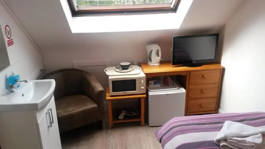 a bedroom with a tv and a chair and a desk at Station View Guest House in Dyce