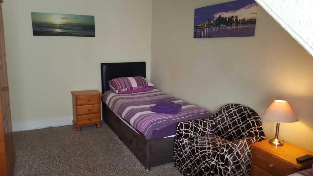 a small bedroom with a bed and a chair at Station View Guest House in Dyce