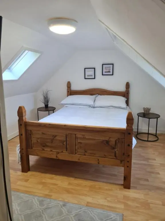 a bedroom with a wooden bed in a attic at Fisherman Cottage - ideal for Trades and couples part of Langley Serviced Apartments Has outside steps in Wick