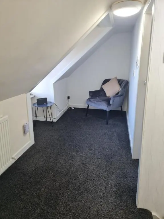 a room with a chair sitting under a staircase at Fisherman Cottage - ideal for Trades and couples part of Langley Serviced Apartments Has outside steps in Wick