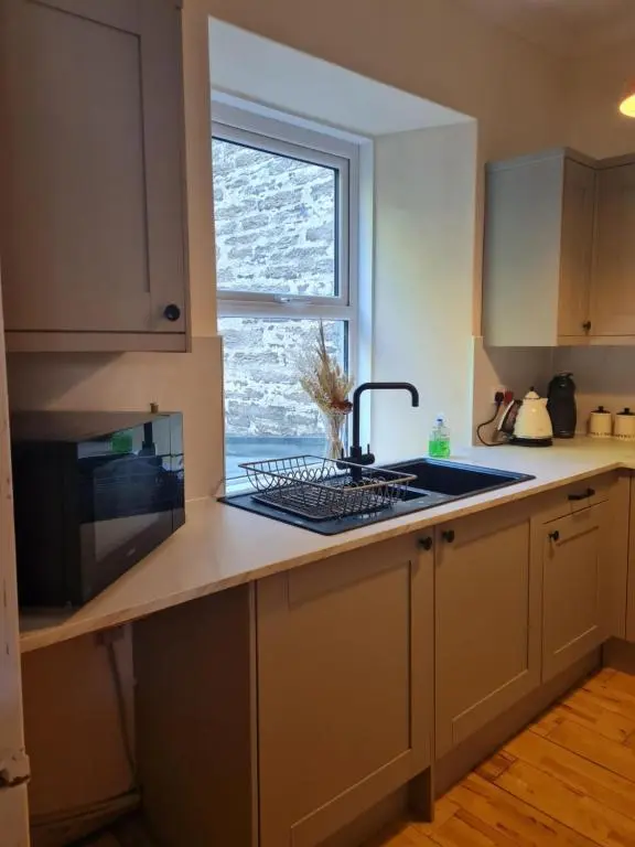 a kitchen with a sink and a window at Fisherman Cottage - ideal for Trades and couples part of Langley Serviced Apartments Has outside steps in Wick