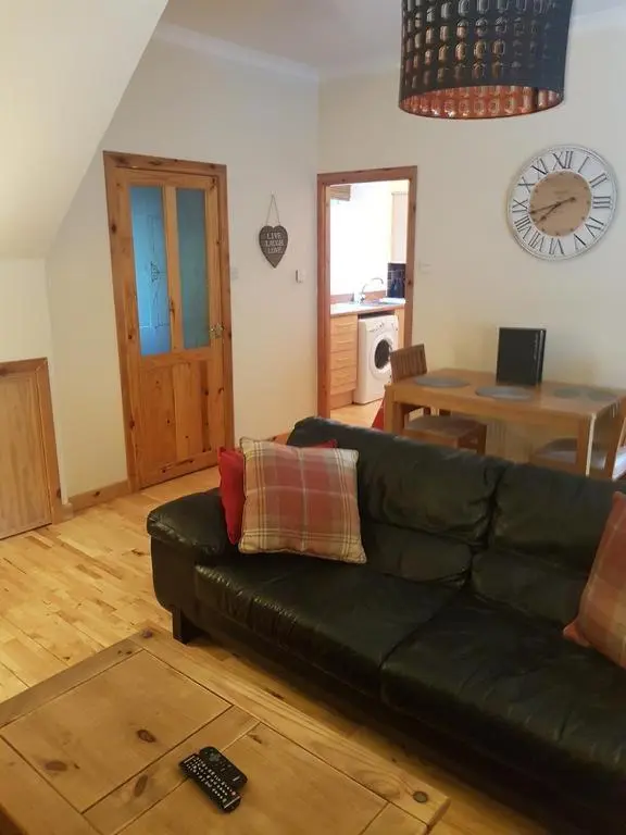 a living room with a black couch and a table at Fisherman Cottage - ideal for Trades and couples part of Langley Serviced Apartments Has outside steps in Wick