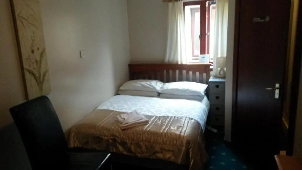 a small bedroom with a bed and a window at Beeches Guest House in Dyce