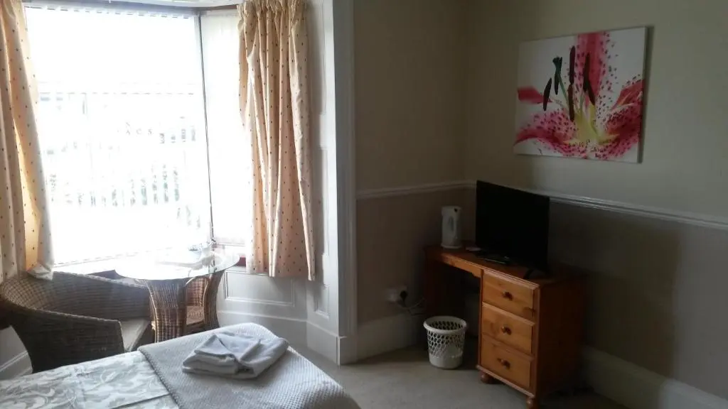 a bedroom with a bed and a television and a window at Beeches Guest House in Dyce