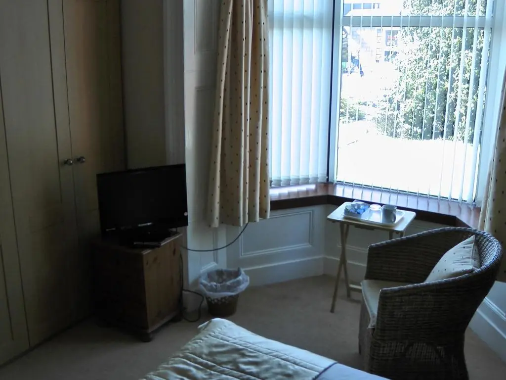 a living room with a television and a chair and a window at Beeches Guest House in Dyce