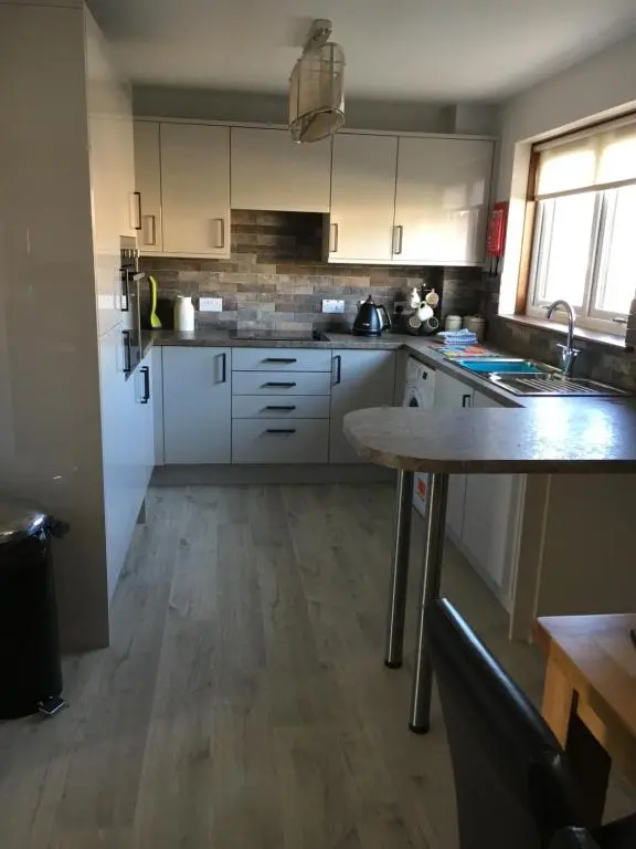a kitchen with white cabinets and a wooden floor at Christiesholidayhomes in Aviemore