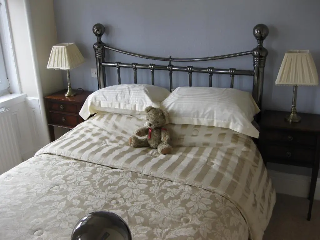 a teddy bear sitting on a bed with pillows at Struan House in Buckie