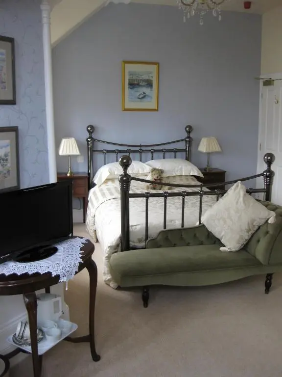 a bedroom with a bed with a green couch and a television at Struan House in Buckie