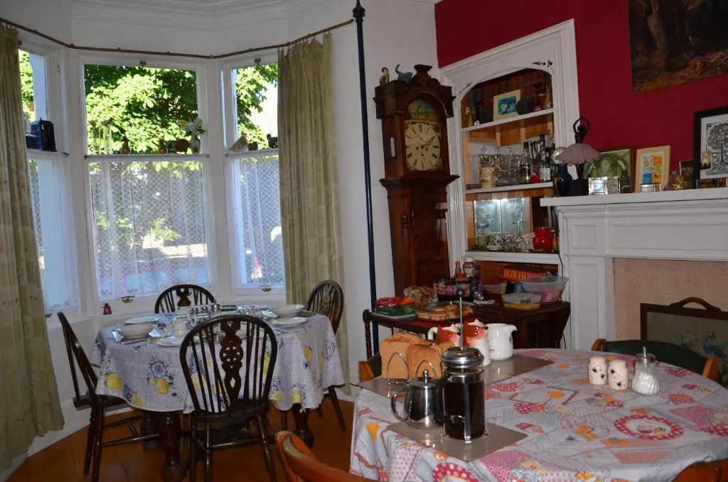 a dining room with a table and a grandfather clock at Averon House in Inverness