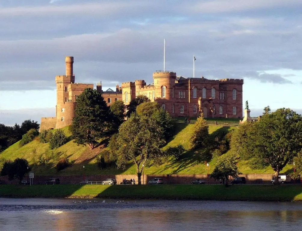a castle on top of a hill next to a body of water at Farraline Court in Inverness