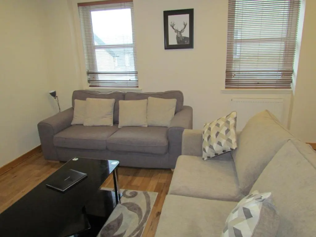 a living room with a couch and a table at Farraline Court in Inverness