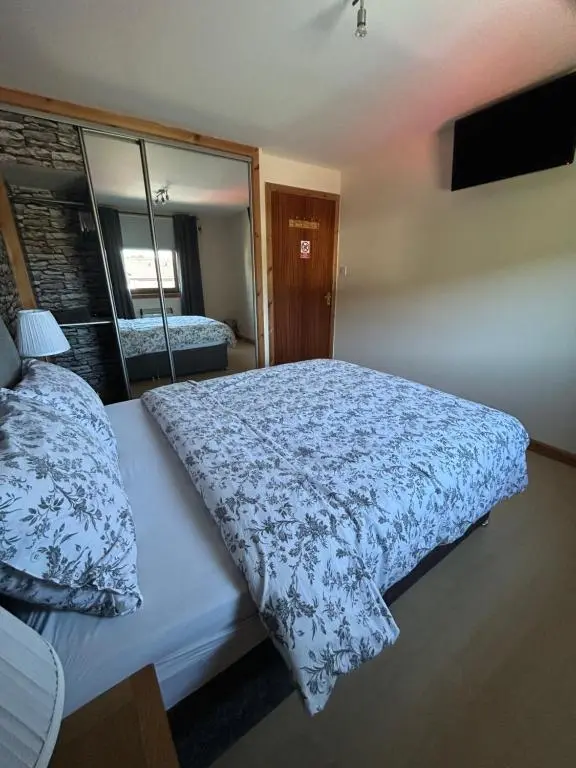 a bedroom with a bed with a blue and white comforter at No 52 - Apartment with Lounge and Dining Area - No kitchen in Ullapool