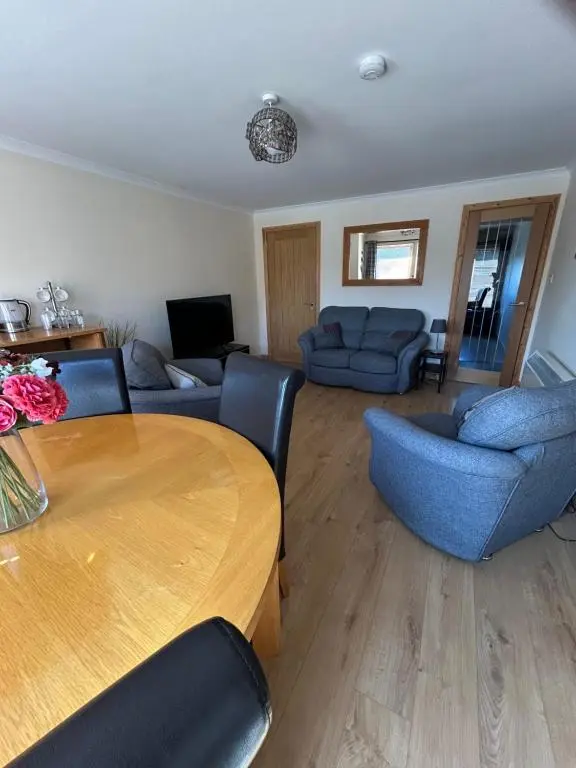 a living room with a wooden table and blue chairs at No 52 - Apartment with Lounge and Dining Area - No kitchen in Ullapool