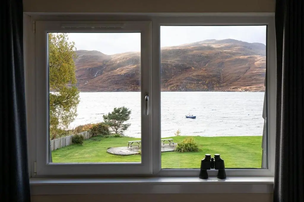 a window with a view of a lake and mountains at Harbour House in Ullapool