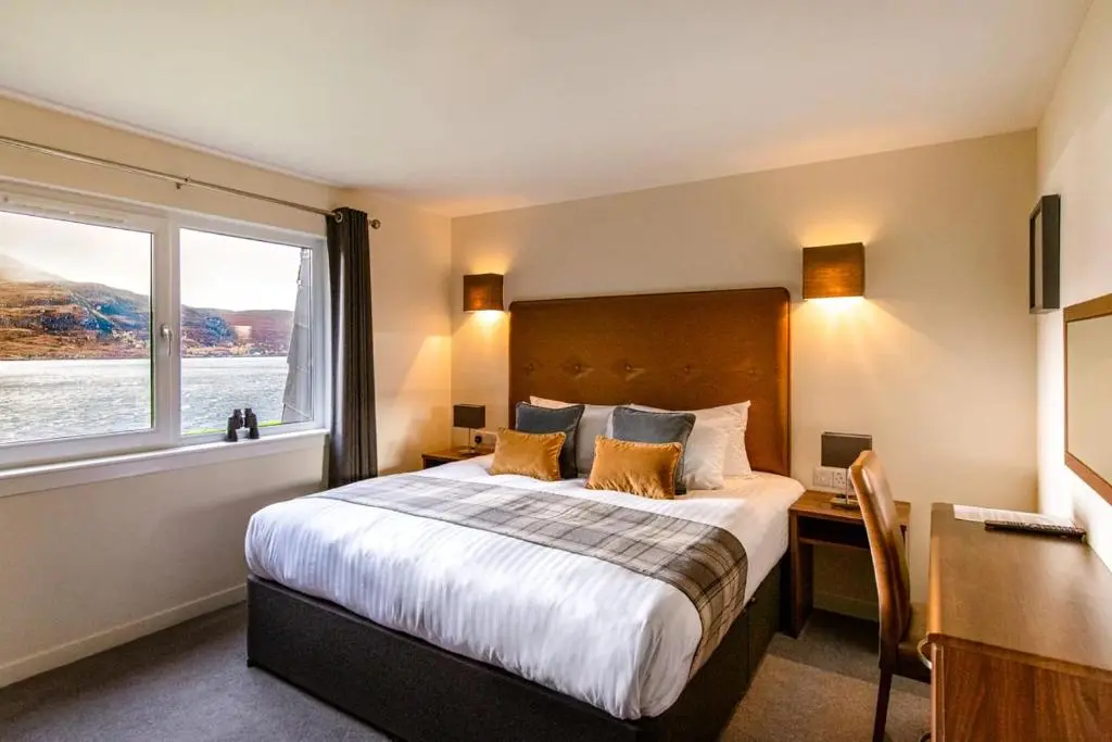 a bedroom with a bed and a desk and a window at Harbour House in Ullapool