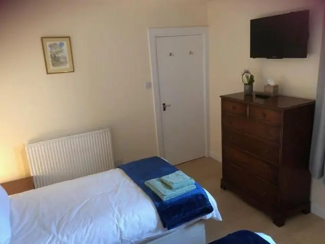a bedroom with a bed and a dresser and a television at Broadsea in Inverurie