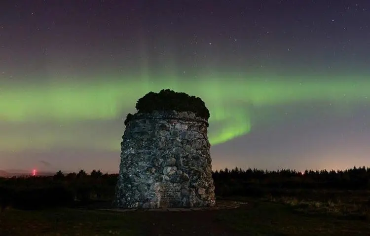 an old stone tower under the green northern lights at Mulberry in Nairn