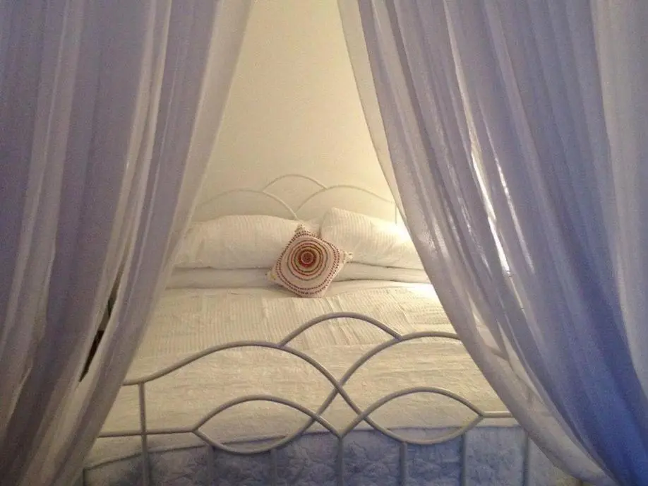 a white bed with white curtains on it at Pew with a View - Seafront Cottages in Sandhaven