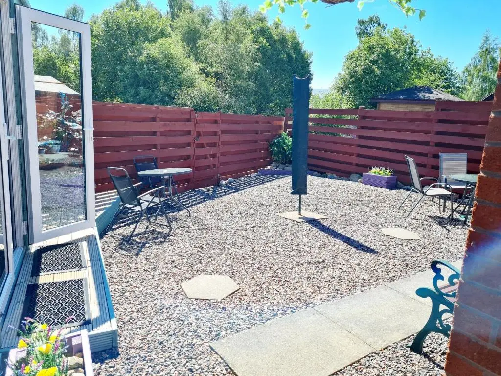 a patio with chairs and a table and a fence at Aviemore Stay & Explore in Aviemore