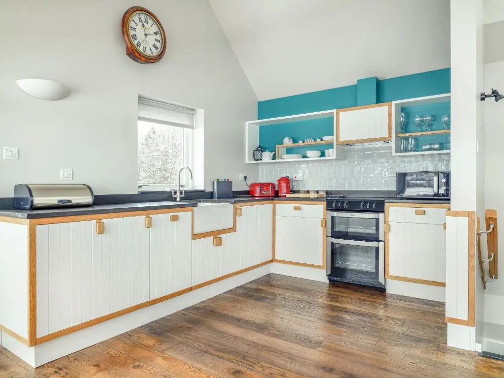 a kitchen with white cabinets and a clock on the wall at Signal Box in Newtonmore