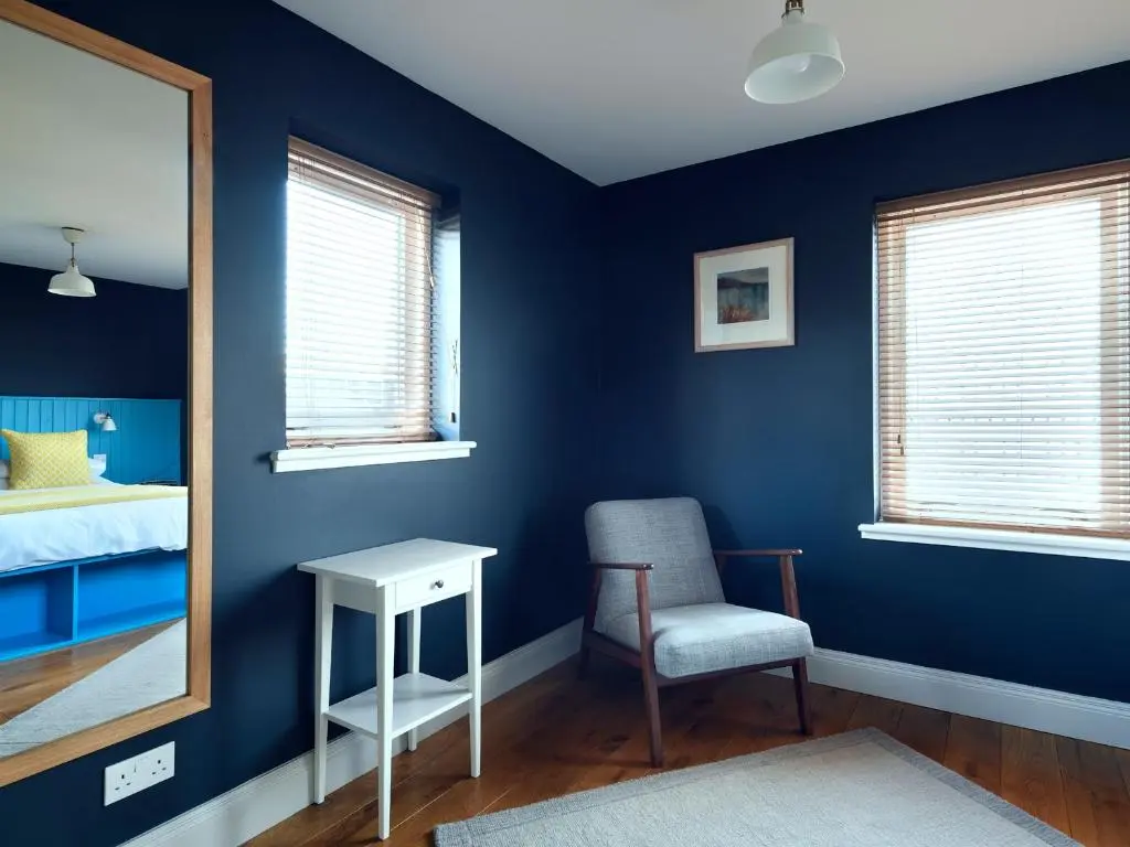 a bedroom with blue walls and a chair and a mirror at Signal Box in Newtonmore