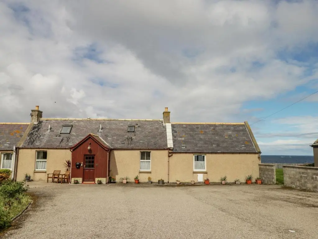 a large yellow house with a gray roof at Braehead Croft in Portessie