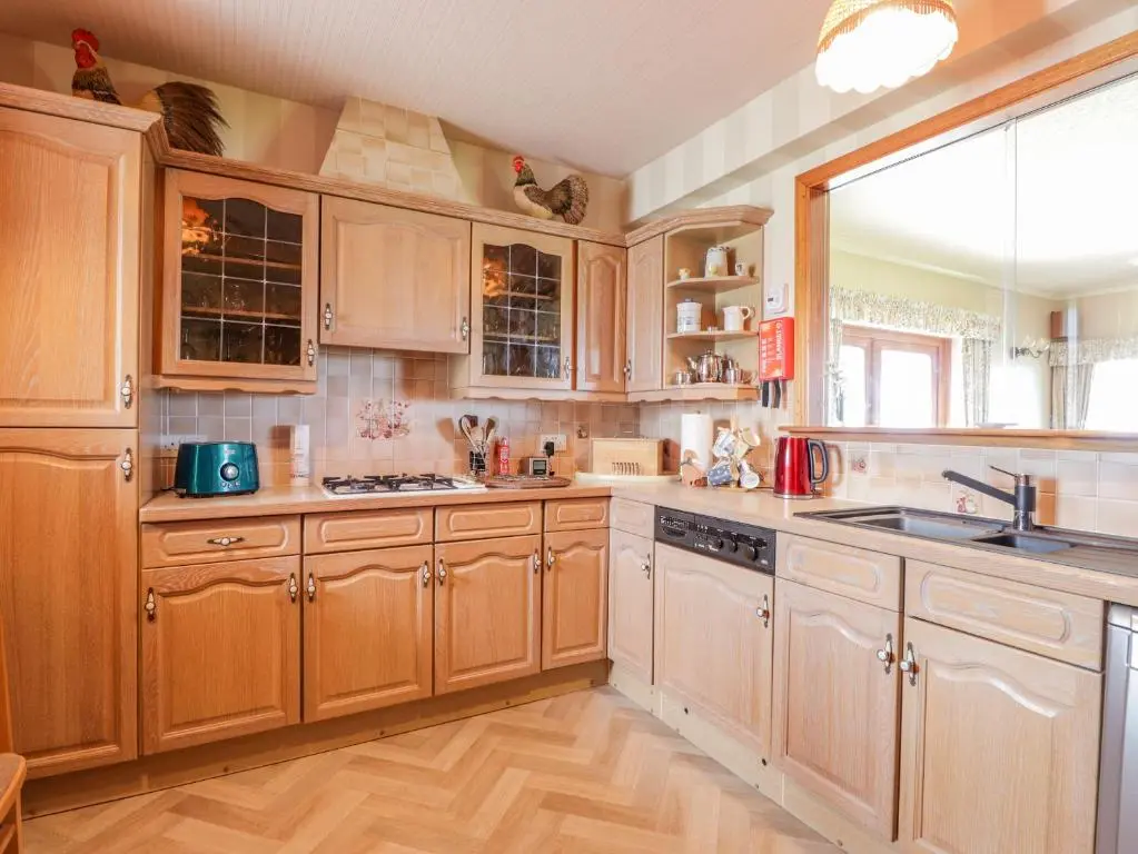 a kitchen with wooden cabinets and a sink and a window at Braehead Croft in Portessie